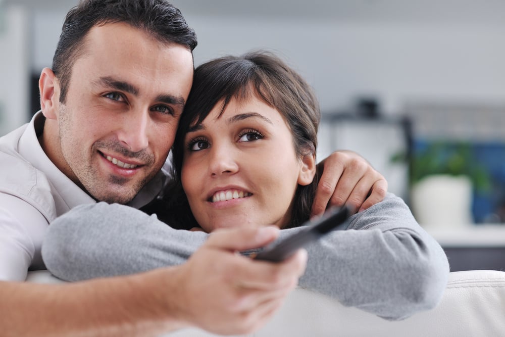 Relaxed young couple watching tv at home in bright living room Relaxed young couple watching tv at home in bright living room
