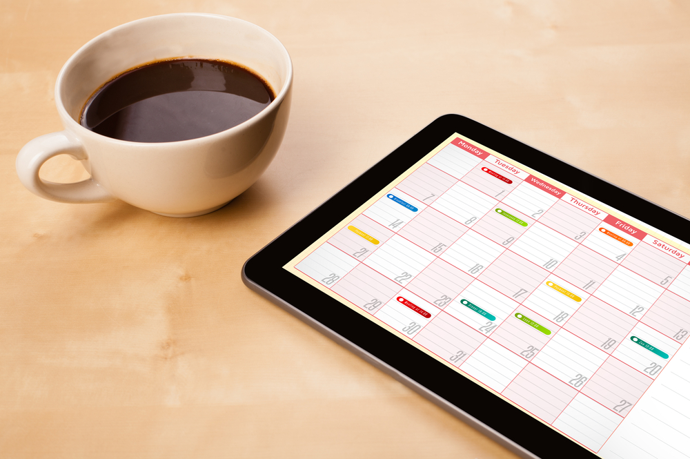 Workplace with tablet pc showing calendar and a cup of coffee on a wooden work table close-up-1